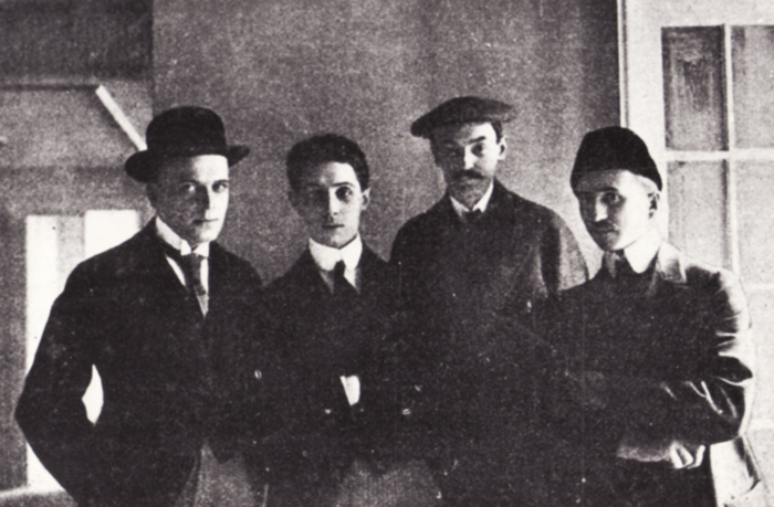 Na czarno białym zdjęciu z 1912 roku stoją CZESŁAW PRZYBYLSKI, ARNOLD SZYFMAN, KAROL FRYCZ, EDWARD TROJANOWSKI.