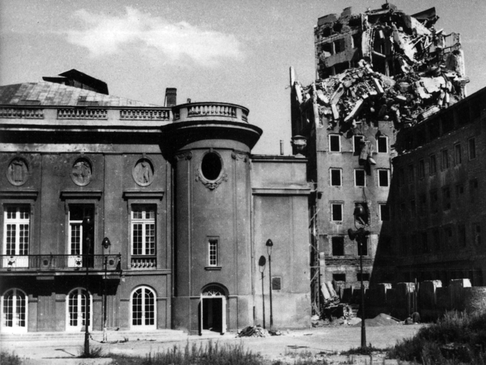 Na czarno białym zdjęciu z 1945 roku widoczny fragment budynku Teatru Polskiego od strony ulicy Karasia oraz fragment zniszczonego budynku Towarzystwa Ubezpieczeń Wzajemnych